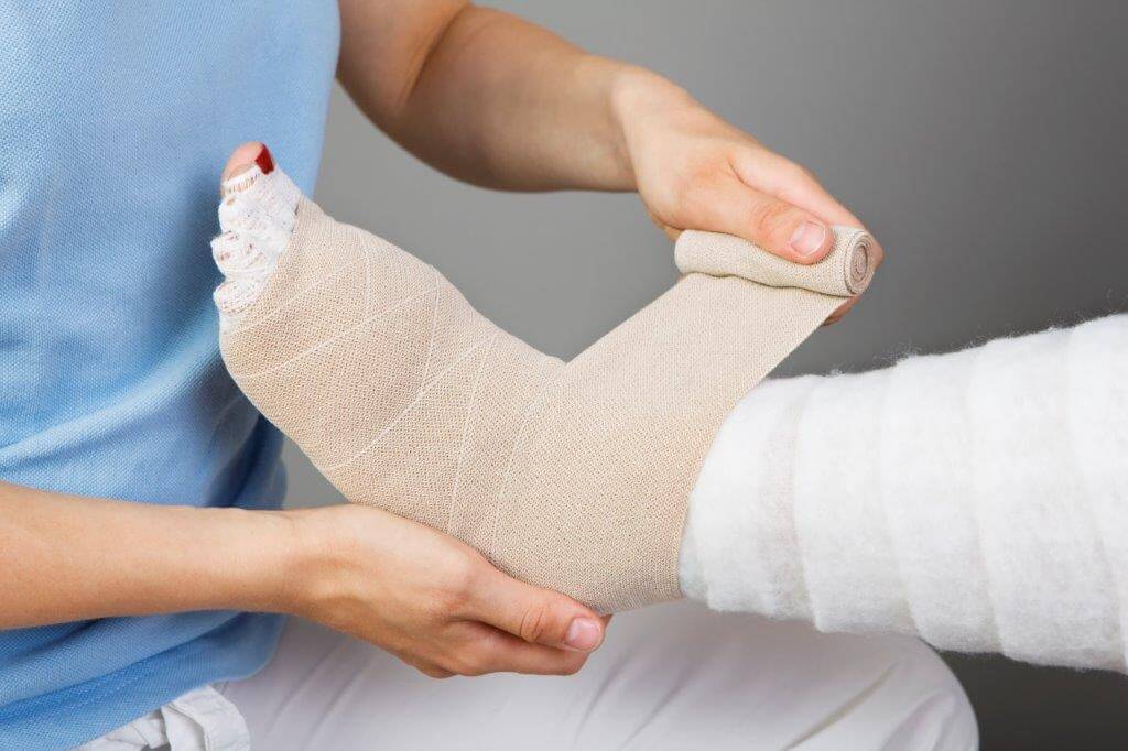 A person's foot and ankle being wrapped with a bandage by an occupational therapist